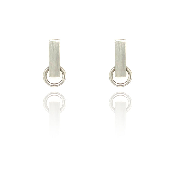 Small City Earrings featuring a chunky brushed sterling silver bar, pierced by a polished silver circle that moves and spins in a kinetic, bold geometric design.